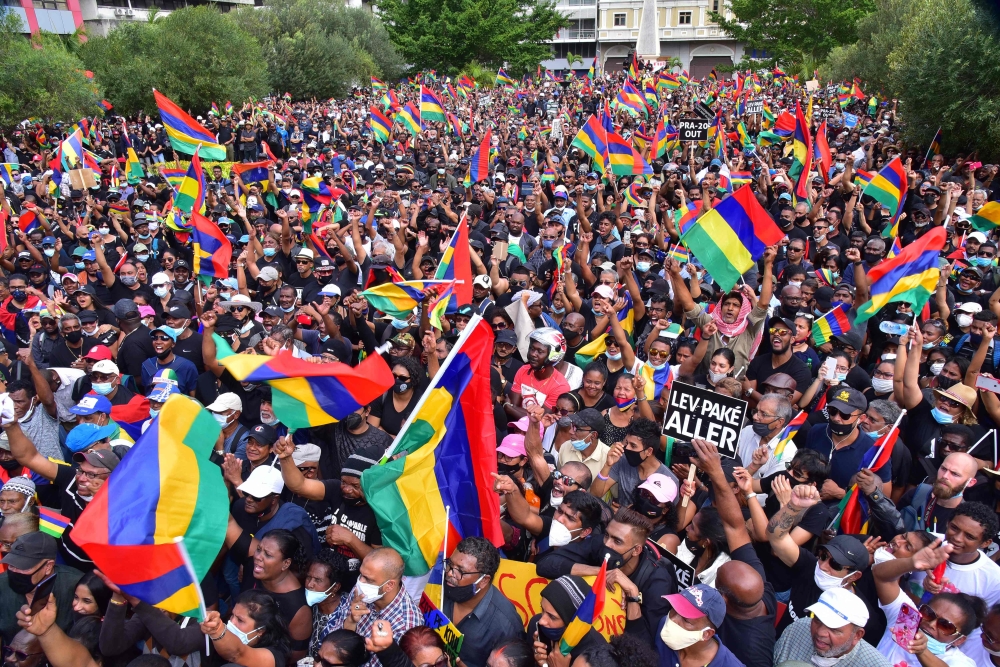 People wave the national flag as they attend a protest against the government's response to the oil spill disaster that happened in early August at St Louis Cathedral in Port Louis, on the island of Mauritius, on August 29, 2020. Beekash Roopun / L'Expres