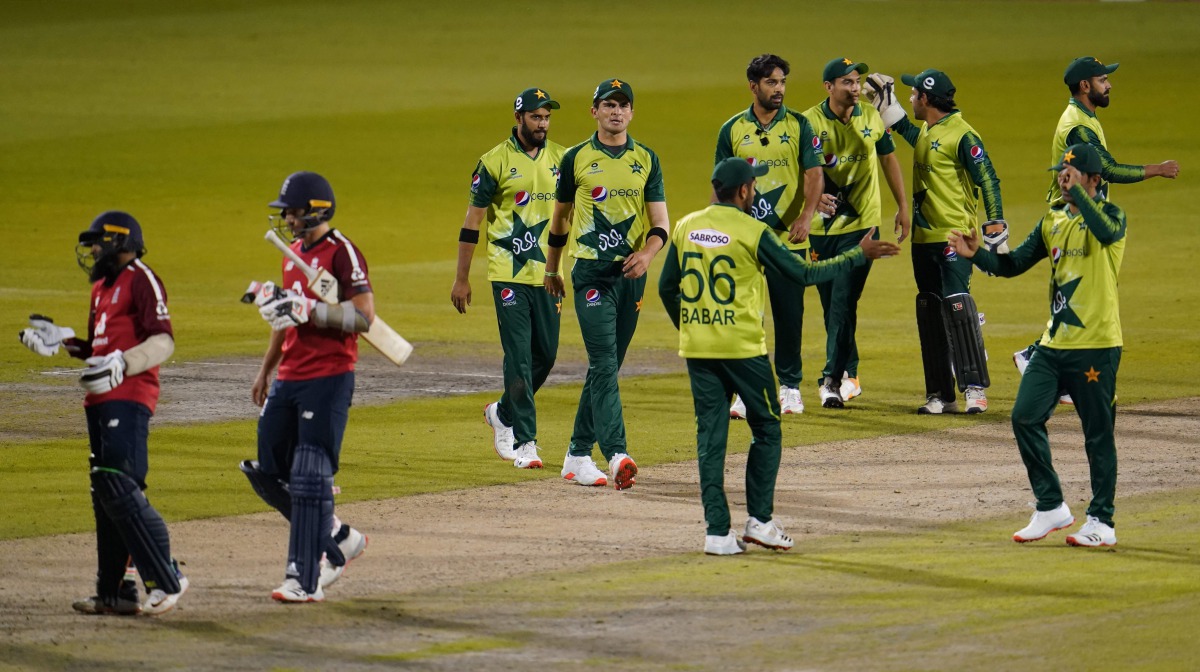 England's Tom Curran and England's Adil Rashid leave the field as Pakistan players celebrate winning by five runs after the international Twenty20 Cricket match between England and Pakistan at Old Trafford Cricket ground in Manchester, north-west England,