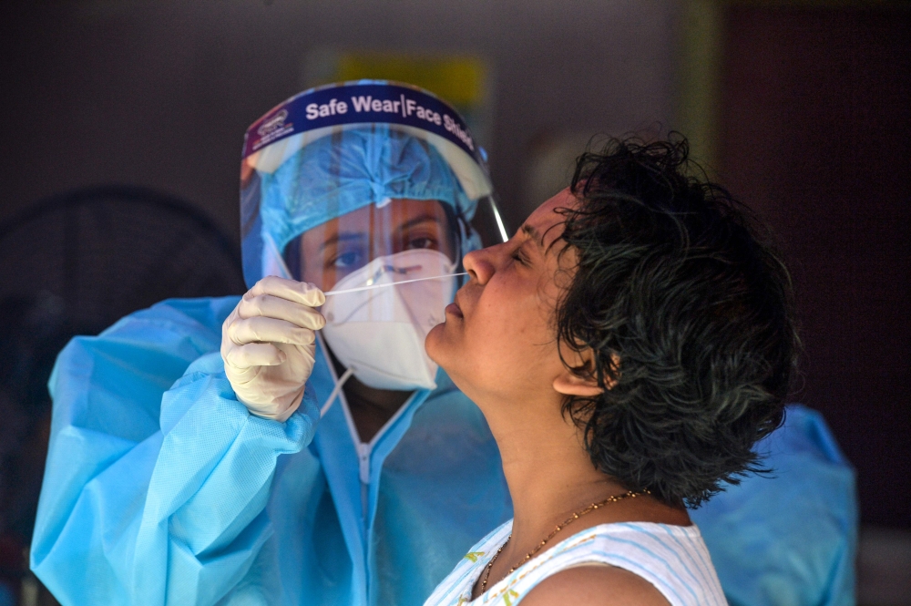 A health official collects nasal swab samples from a woman (R) for a Covid-19 coronavirus test at a primary health centre in Siliguri on September 5, 2020. AFP / Diptendu DUTTA