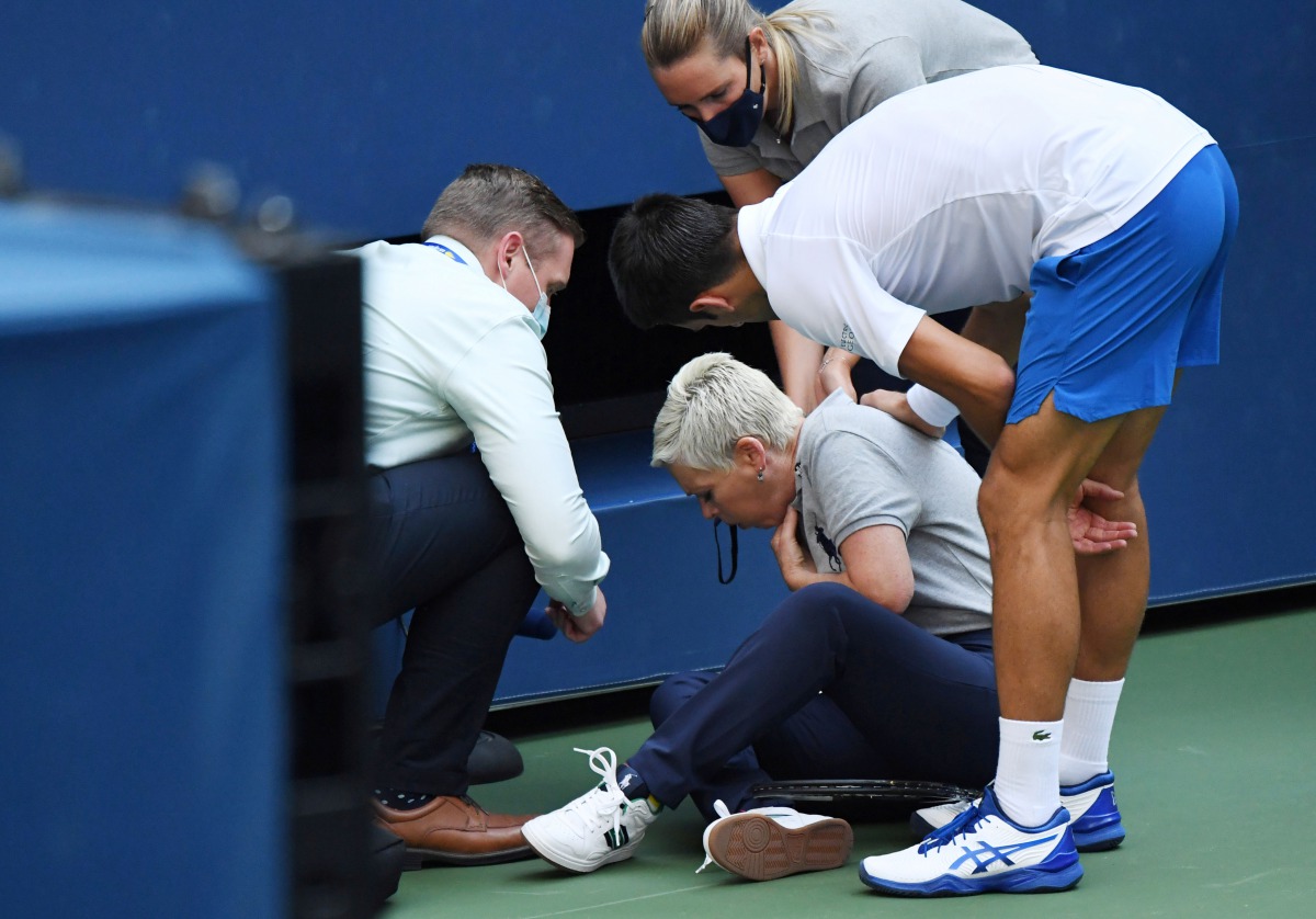 Sep 6, 2020; Flushing Meadows, New York, USA; Novak Djokovic of Serbia and a tournament official tend to a linesperson who was struck with a ball by Djokovic against Pablo Carreno Busta of Spain (not pictured) on day seven of the 2020 U.S. Open tennis tou