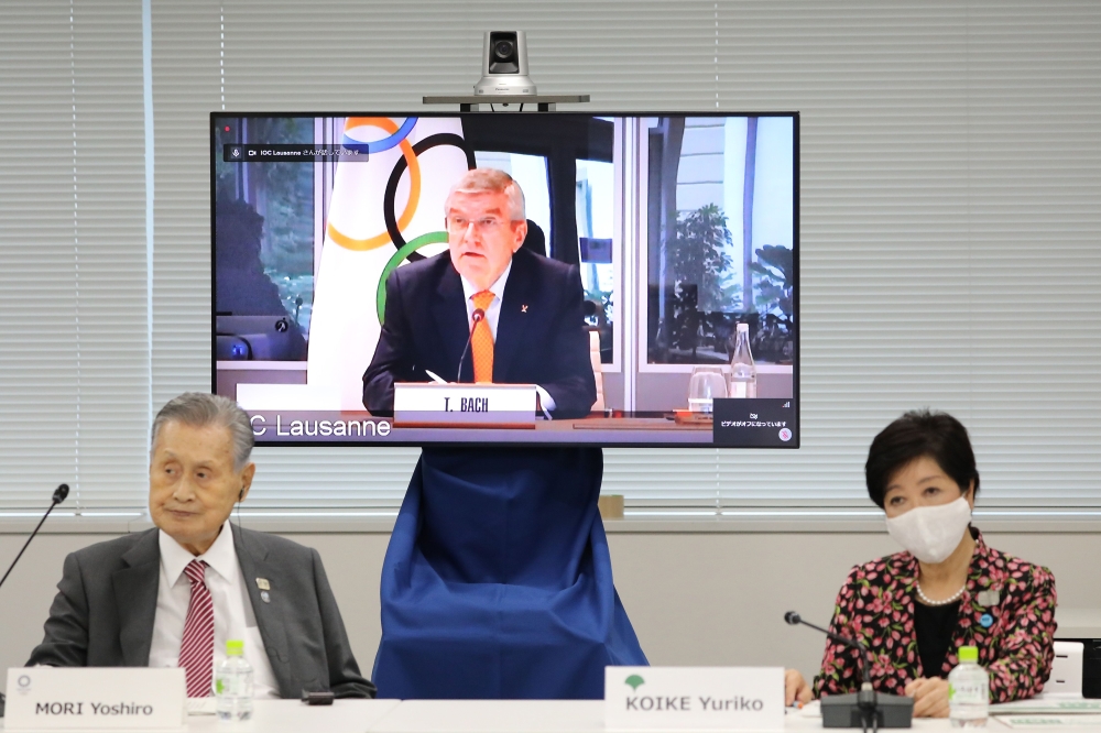 President of the Tokyo 2020 Organising Committee Yoshiro Mori (L) and Tokyo governor Yuriko Koike (R) listen as International Olympic Committee (IOC) president Thomas Bach (on screen) speaks during a video meeting of the IOC Coordination Commission for th