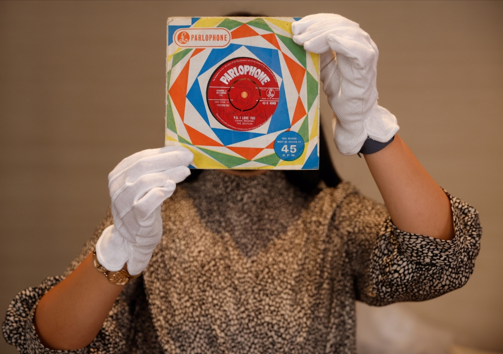 A member of staff poses for a photograph with a first pressing of the record 