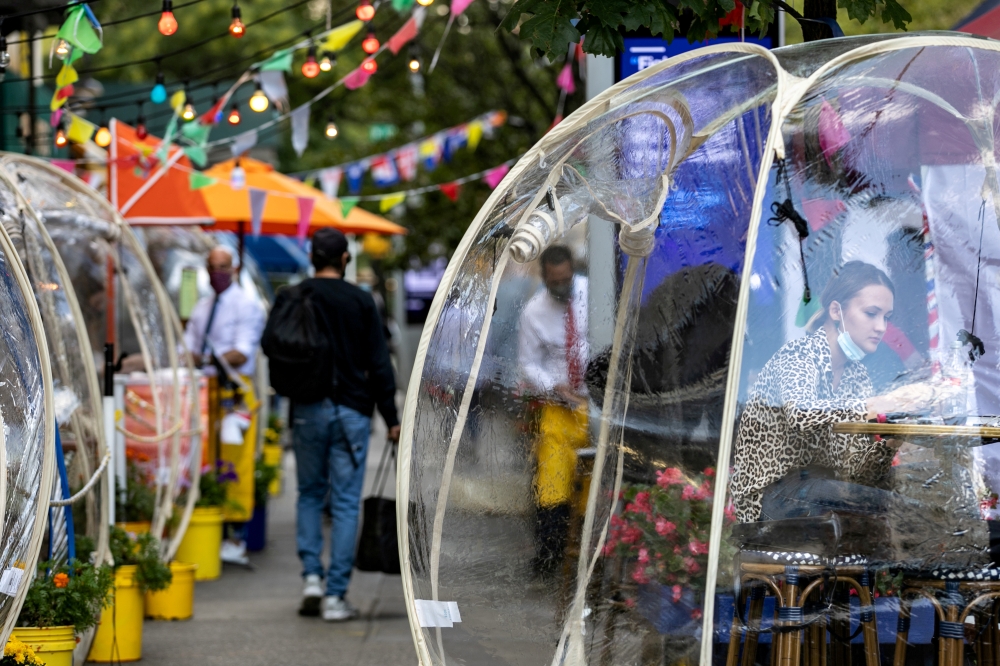 A woman sits outside Cafe Du Soleil under bubble tents following the outbreak of the coronavirus disease (COVID-19) in the Manhattan borough of New York City, New York, U.S., September 23, 2020. REUTERS/Jeenah Moon/File Photo