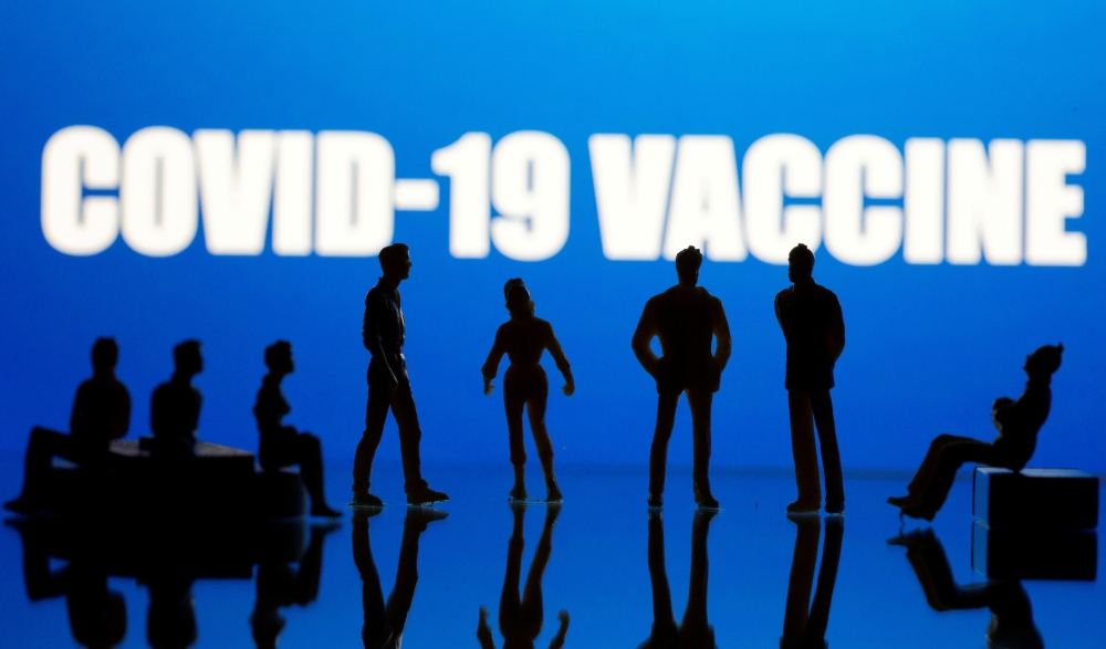 Small toy figures are seen in front of a Covid-19 Vaccine logo in this illustration taken, September 9, 2020. REUTERS/Dado Ruvic/Illustration/File Photo