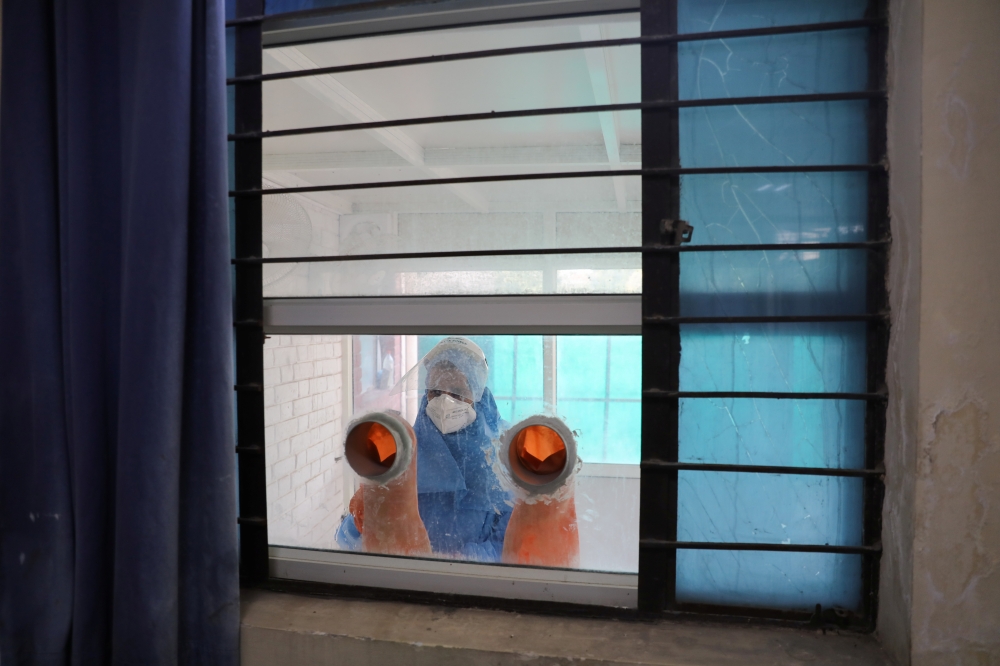 A healthcare worker sanitizes the partition made in window for testing amidst the spread of the coronavirus disease (COVID-19), at a railway station, in New Delhi, India October 9, 2020. Reuters/Anushree Fadnavis