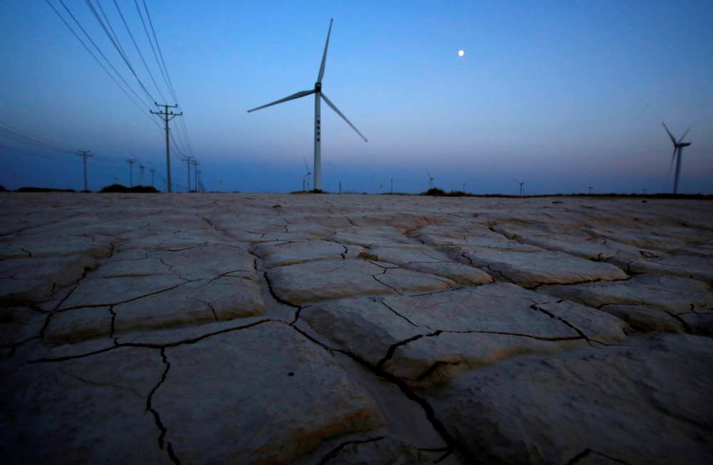 Cracked earth marks a dried-up area near a wind turbine used to generate electricity at a wind farm in Guazhou, 950km (590 miles) northwest of Lanzhou, Gansu Province September 15, 2013. REUTERS/Carlos Barria/File Photo