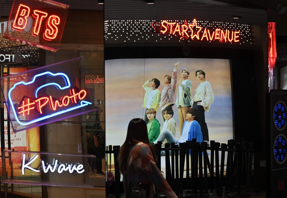 A commercial poster showing K-pop group BTS members is reflected in a mirror at a duty free shop in Seoul on October 15, 2020. / AFP / Jung Yeon-je