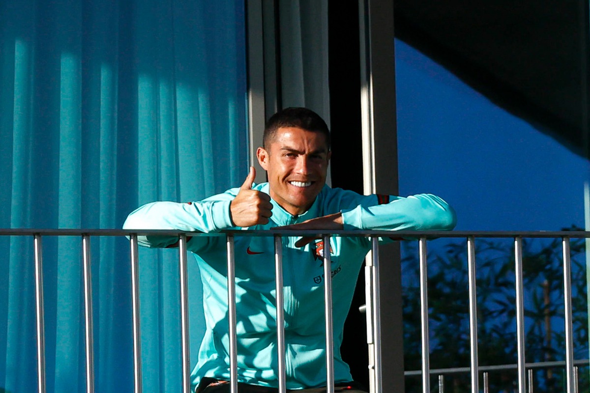 TOPSHOT - This handout picture released on October 13, 2020 by the Portuguese Football Federation shows Portugal´s forward Cristiano Ronaldo giving the thumb up as he watches his teammates training session from a balcony at Portugal´s training camp in Oei