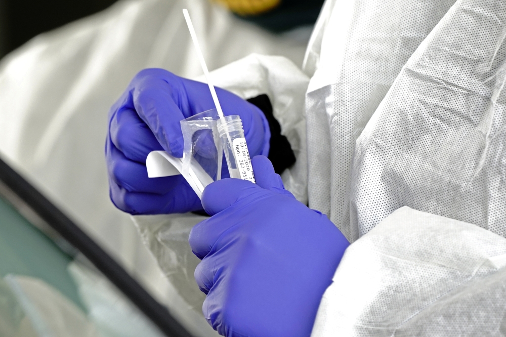 A nurse holds a patient's freshly collected nasal swab at a coronavirus disease (COVID-19) drive-thru testing site at Froedtert North Hills Health Center in Menomonee Falls, Wisconsin, U.S., October 18, 2020. REUTERS/Bing Guan