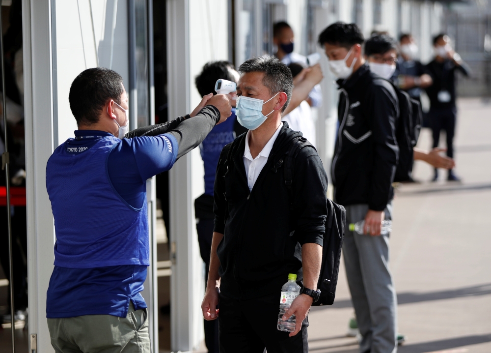 Officials check body temperature of people acting as spectators during screening measures test, hosted by Tokyo Organising Committee of the Olympic and Paralympic Games, ahead of the summer games that have been postponed to 2021 due to the coronavirus dis