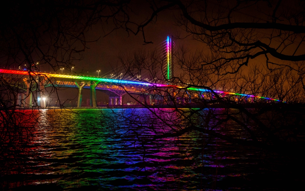 TOPSHOT - Samuel de Champlain Bridge is illuminated in the colors of the rainbow as a symbol of support during the novel coronavirus pandemic in Montreal, Quebec, Canada, on April 19, 2020. / AFP / Sebastien St-Jean
