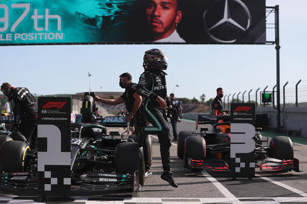 Mercedes' British driver Lewis Hamilton (C) gets-off his car after taking the pole position after the qualifying session at the Autodromo Internacional do Algarve on October 24, 2020 in Portimao ahead of the Portuguese Formula One Grand Prix. / AFP /JOSE 