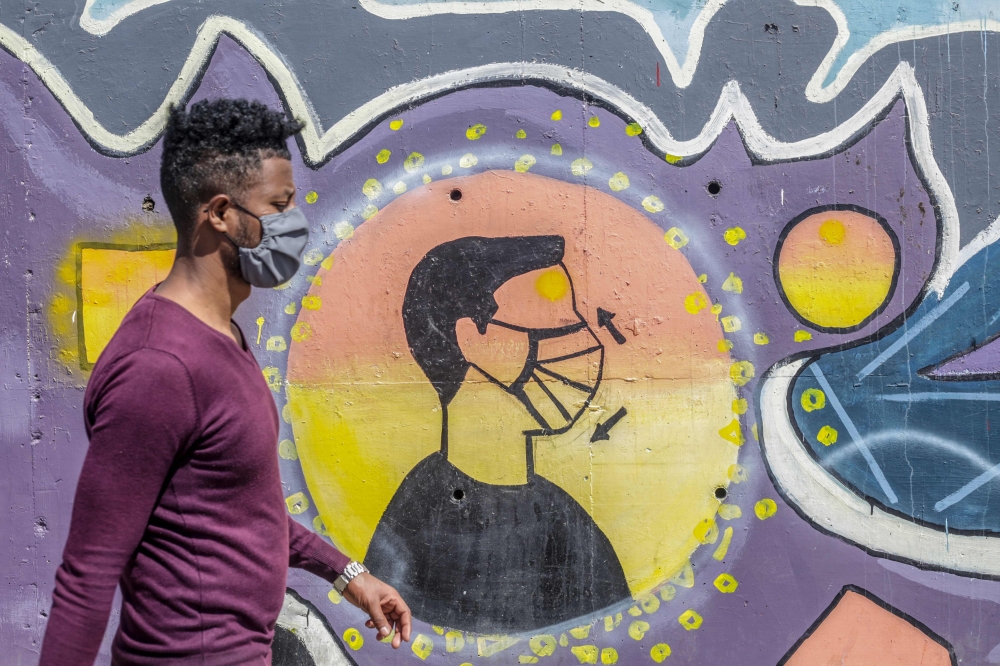 A man wearing a face mask walks past an advocacy graffiti urging for mask wearing amid the COVID-19 coronavirus pandemic in Addis Ababa, Ethiopia on October 26, 2020. / AFP / AMANUEL SILESHI