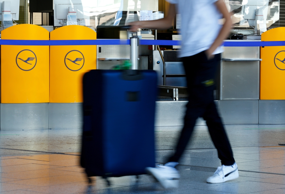FILE PHOTO: A passenger walks past a Lufthansa ticket counter at Frankfurt Airport in Frankfurt, Germany, September 21, 2020. REUTERS/Ralph Orlowski