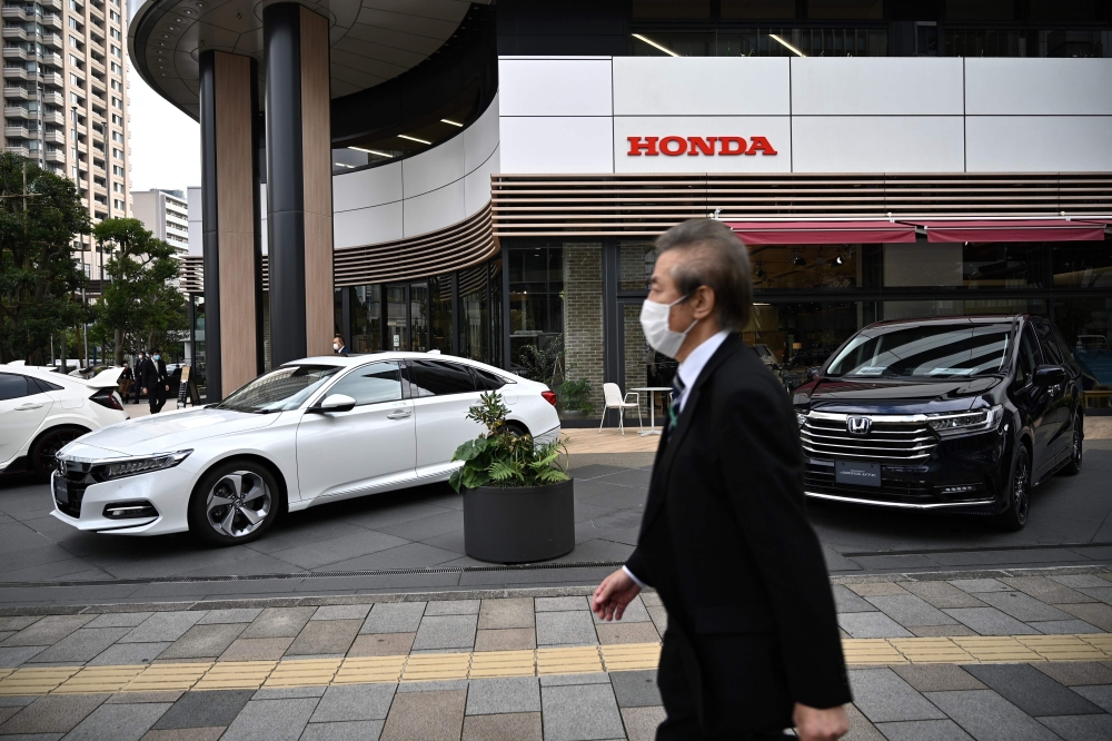 A man walks past cars displayed outside a Honda showroom of company’s headquarters in Tokyo on November 6, 2020. / AFP / Philip FONG