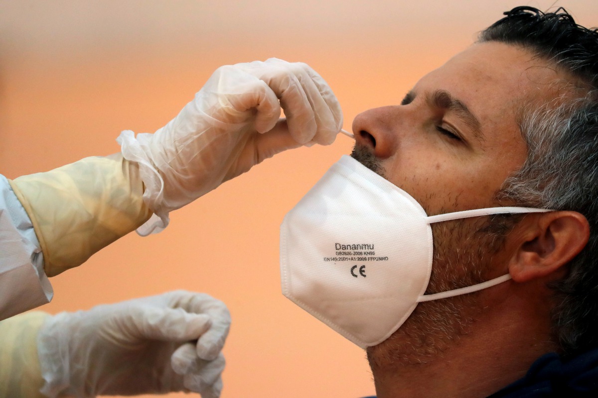 FILE PHOTO: A healthcare worker takes a swab sample from a man to be tested for the coronavirus disease (COVID-19) during a massive test in the small Andalusian village of Arriate, Spain November 7, 2020. REUTERS/Jon Nazca/File Photo
