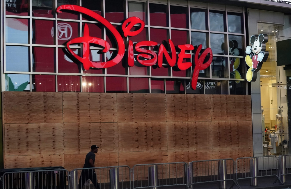 In this file photo taken on June 01, 2020 a man walks past a boarded up Disney store in Times Square shorty before the 11 p.m. curfew went into effect, as demonstrators rallied across the five boroughs Demonstrations are being held across the US after Geo