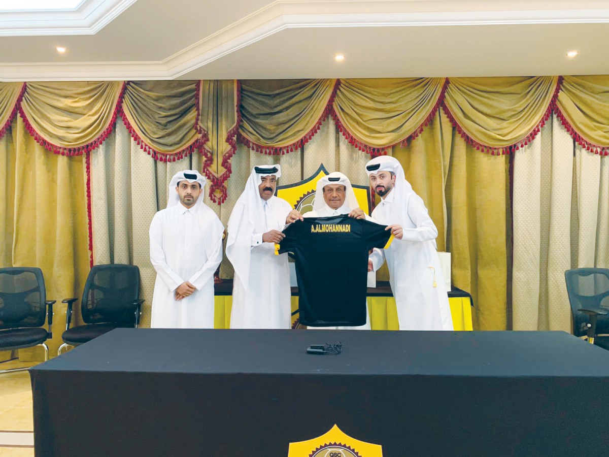 Qatar SC officials holding a team jersey with Ahmed Khalil Al Mohannadi during the ceremony.