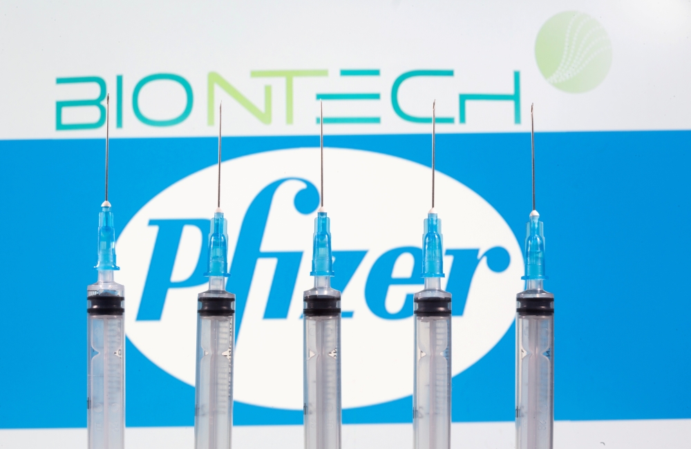 FILE PHOTO: Syringes are seen in front of displayed Biontech and Pfizer logos in this illustration taken November 10, 2020. REUTERS/Dado Ruvic/Illustration