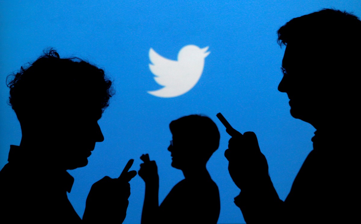 FILE PHOTO: People holding mobile phones are silhouetted against a backdrop projected with the Twitter logo in this illustration picture taken September 27, 2013. REUTERS/Kacper Pempel/Illustration/File Photo
