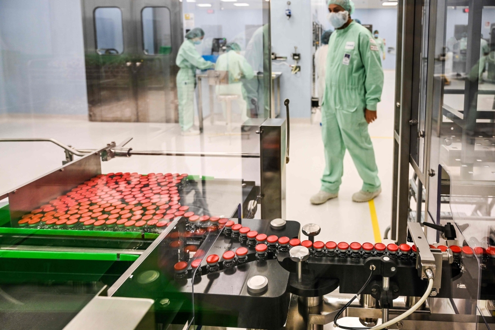 A laboratory technician supervises capped vials during filling and packaging tests for the large-scale production and supply of the University of Oxford’s COVID-19 vaccine candidate, AZD1222, conducted on a high-performance aseptic vial filling line on Se