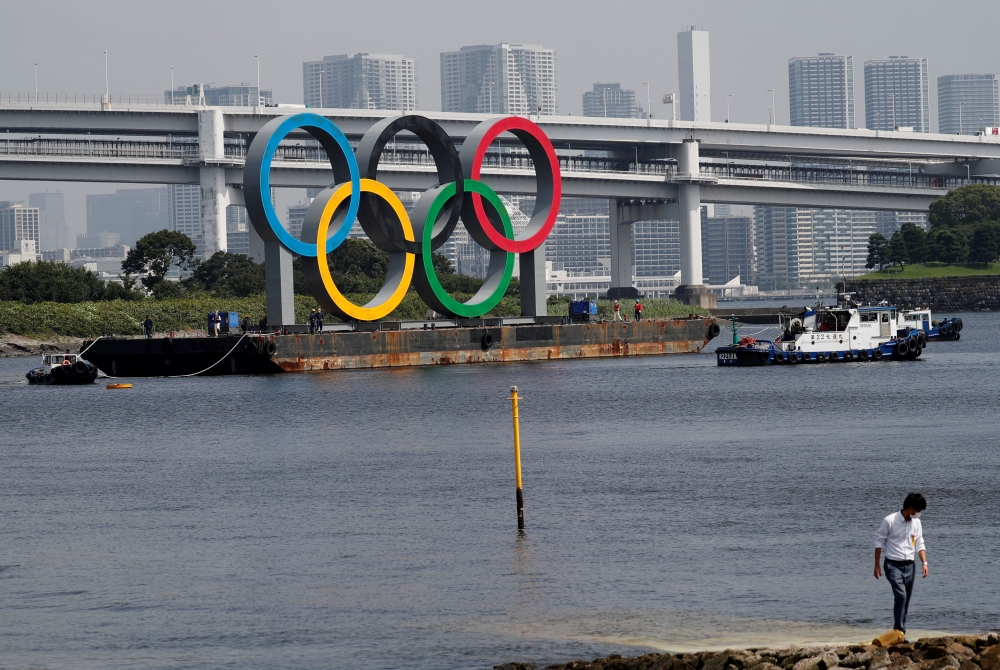 Boats tow the giant Olympic rings, which are being temporarily removed for maintenance, amid the coronavirus disease (COVID-19) outbreak, at the waterfront area at Odaiba Marine Park in Tokyo, Japan August 6, 2020. REUTERS/Kim Kyung-Hoon/File Photo