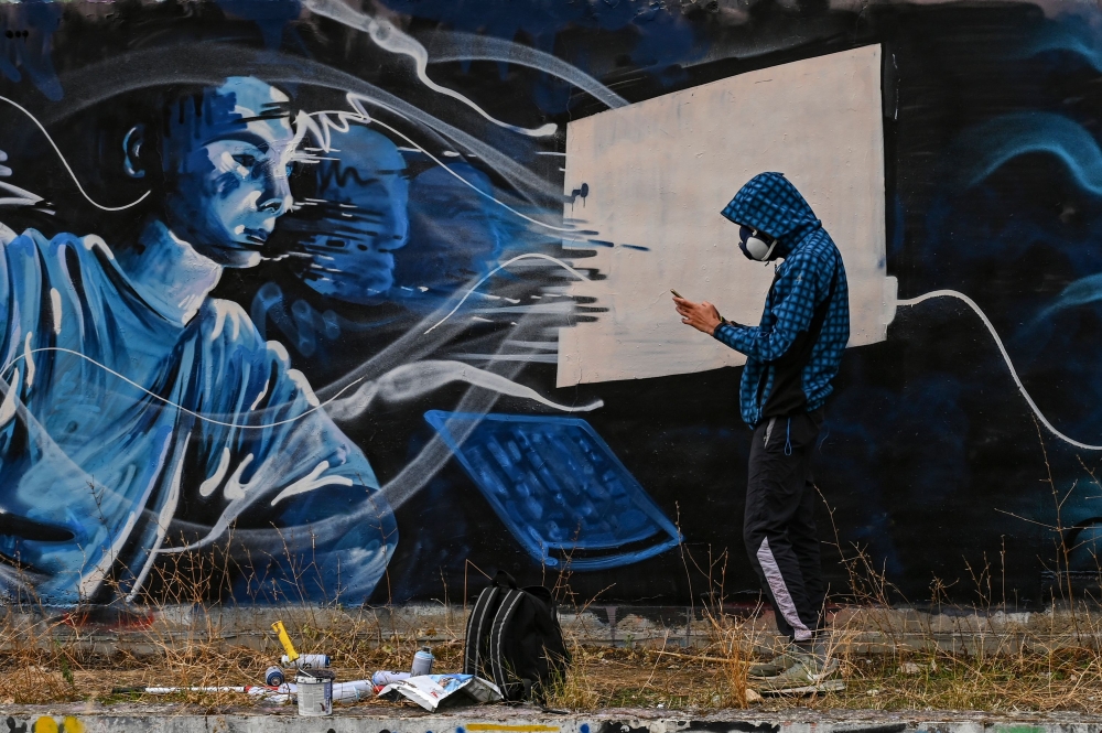 Street artist SF paints a mural on a wall, inspired by the 2nd lockdown in Greece due to the covid_19 pandemic in Athens on November 25, 2020. / AFP / ARIS MESSINIS
