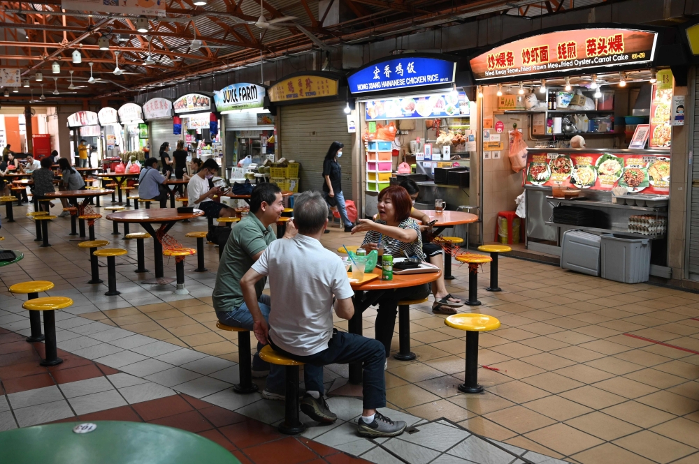 People have their lunch at the Maxwell market hawker centre in Singapore on December 17, 2020, a day after Singapore's street food culture was included on a United Nations Educational, Scientific and Cultural Organization (UNESCO) list of intangible cultu