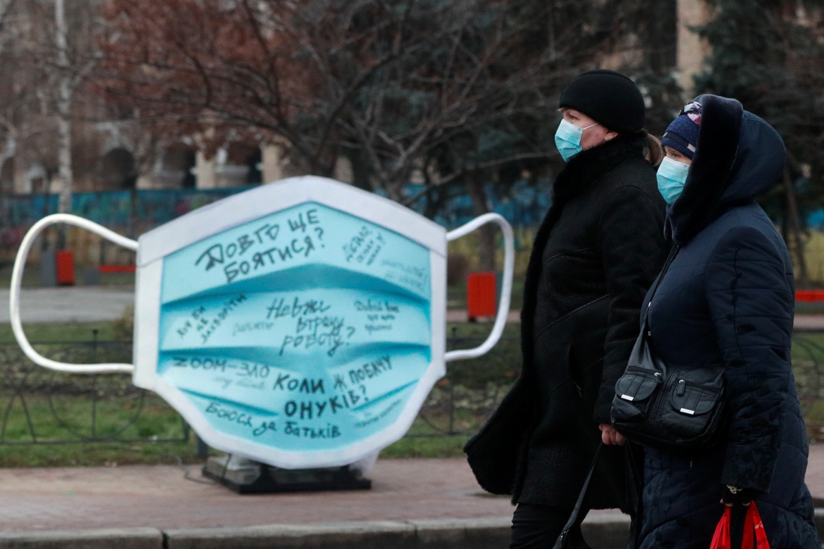 Women walk past an installation showing a protective face mask amid the coronavirus disease (COVID-19) outbreak in Kyiv, Ukraine December 28, 2020. REUTERS/Valentyn Ogirenko
