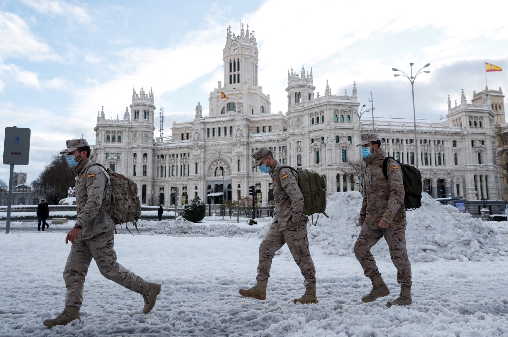 Members of the military walk past the City Hall building after heavy snowfall in Madrid, Spain January 10, 2021. Reuters/Susana Vera