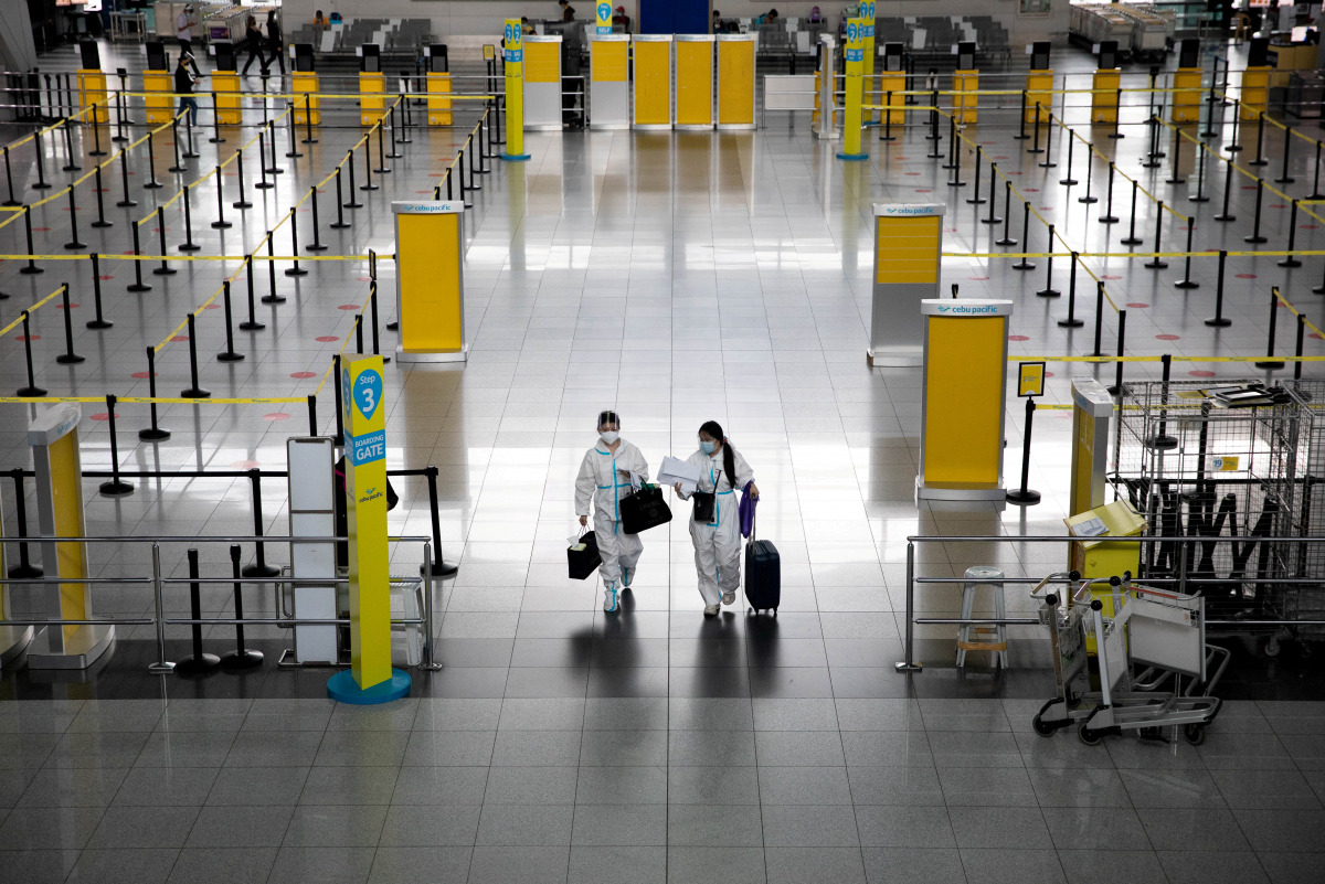 FILE PHOTO: Passengers wearing hazmat suits for protection against the coronavirus disease (COVID-19) walk inside the Ninoy Aquino International Airport in Paranaque, Metro Manila, Philippines, January 14, 2021. REUTERS/Eloisa Lopez/File Photo
