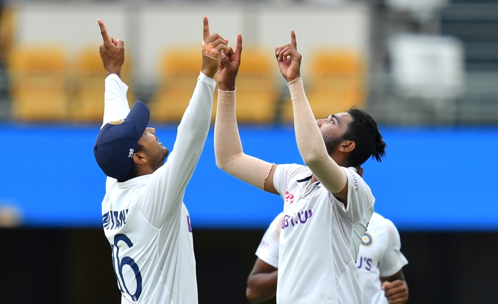 Mohammed Siraj of India celebrates with Mayank Agarwal after getting the wicket of Josh Hazlewood of Australia during day four of the fourth test match between Australia and India at the Gabba in Brisbane, Australia, January 18, 2021. AAP Image/Darren Eng
