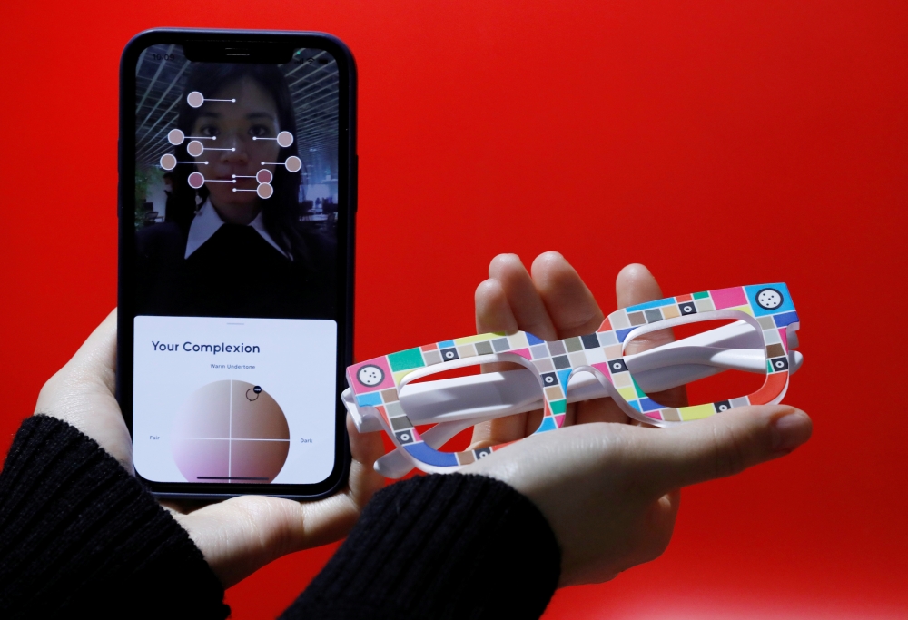 An employee of online fashion retailer Zozo Inc, poses with Zozoglass and its smartphone application, used to measure skin tone for ordering cosmetics online, during a demonstration at the company's office in Tokyo, Japan, January 28, 2021. Picture taken 