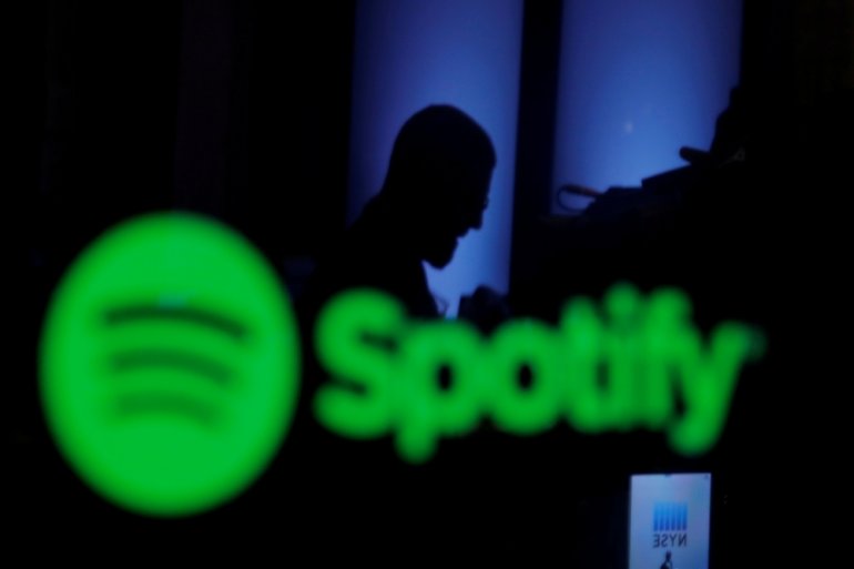 A trader is reflected in a computer screen displaying the Spotify brand before the company begins selling as a direct listing on the floor of the New York Stock Exchange in New York, U.S., April 3, 2018. REUTERS/Lucas Jackson/File Photo