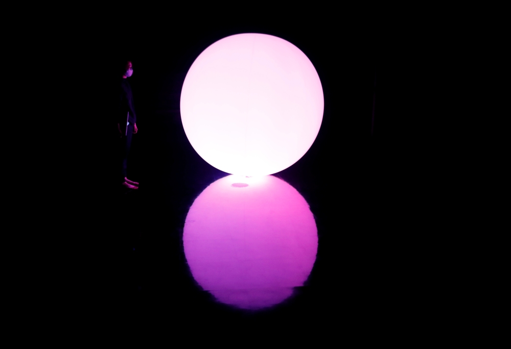 A staff of TeamLab stands next to a digital artwork titled as Levitation during a demonstration of TikTok TeamLab Reconnect, digital artwork combined with sauna, ahead of its opening to the public this month in Tokyo, Japan, March 13, 2021. REUTERS/Kim Ky