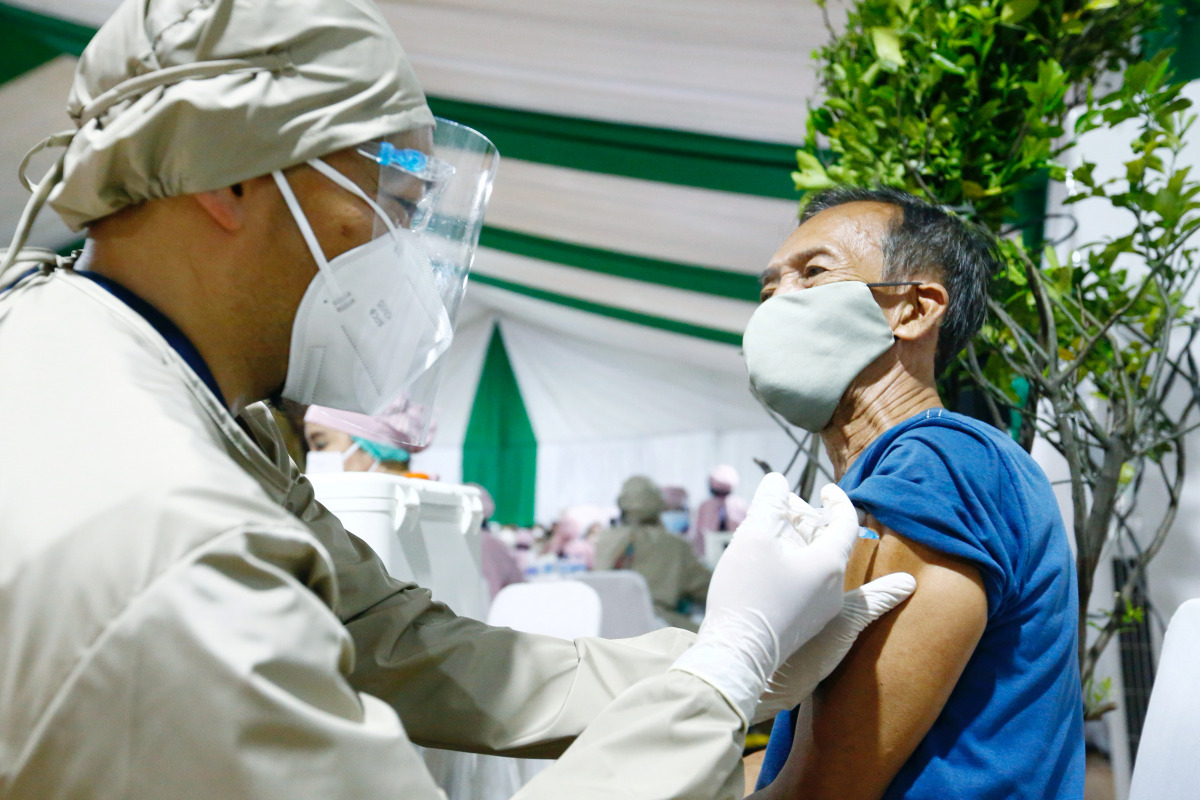 FILE PHOTO: A man reacts while receiving his first dose of China's Sinovac Biotech vaccine for the coronavirus disease (COVID-19) during the mass vaccination program for elderly people at Indonesia's health ministry in Jakarta, Indonesia, March 2, 2021. R