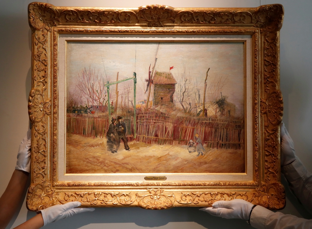 Sotheby's Paris employees pose with the 1887 painting of a Paris street scene 