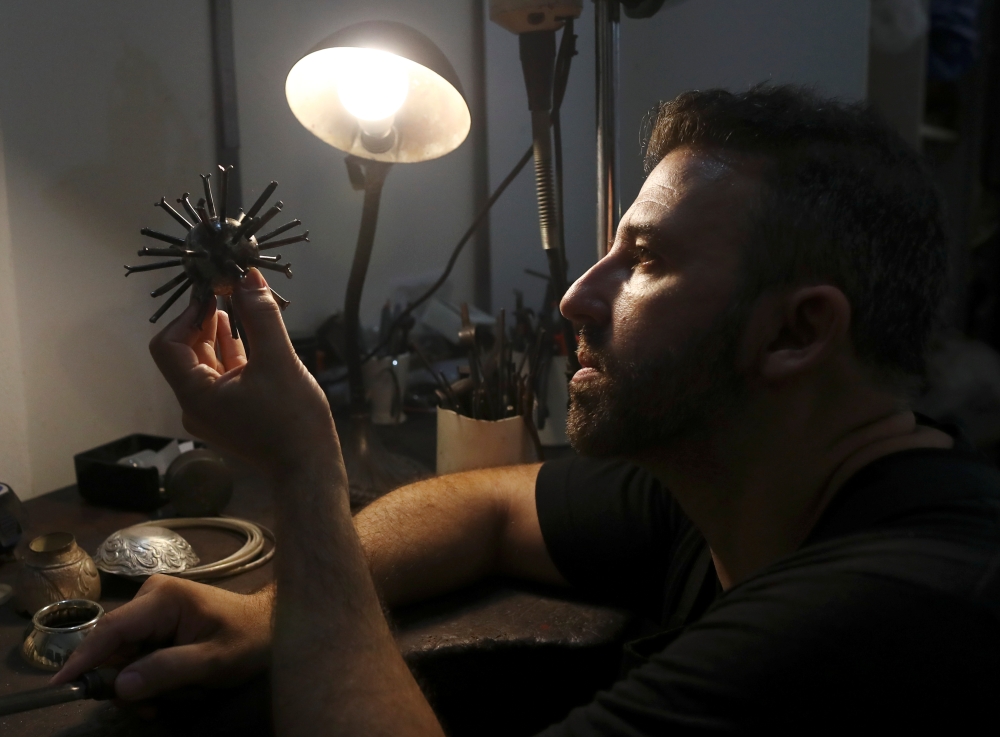 Argentine artist Marcelo Toledo works on an art piece depicting a coronavirus virion made from iron that will be part of the 