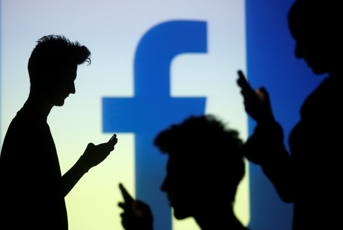 FILE PHOTO: People are silhouetted as they pose with mobile devices in front of a screen projected with a Facebook logo, in this picture illustration taken in Zenica October 29, 2014. REUTERS/Dado Ruvic/File Photo
