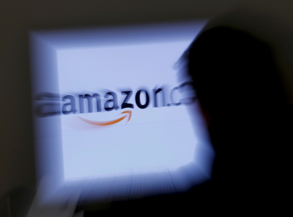 A zoomed illustration image of a man looking at a computer monitor showing the logo of Amazon is seen in Vienna November 26, 2012. REUTERS/Leonhard Foeger/File Photo