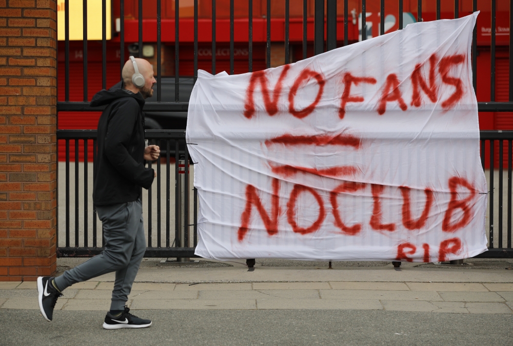 A man runs past anti Super League banners outside Anfield as twelve of Europe's top football clubs launch a breakaway REUTERS/Phil Noble