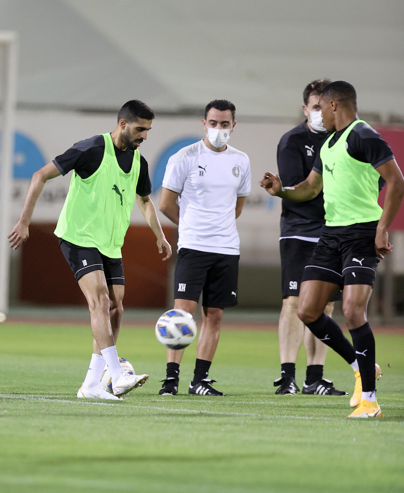 Al Sadd captain Hassan Al Haydos (left) practises with the ball as
Xavi Hernandez (second right) looks on during a training session. 