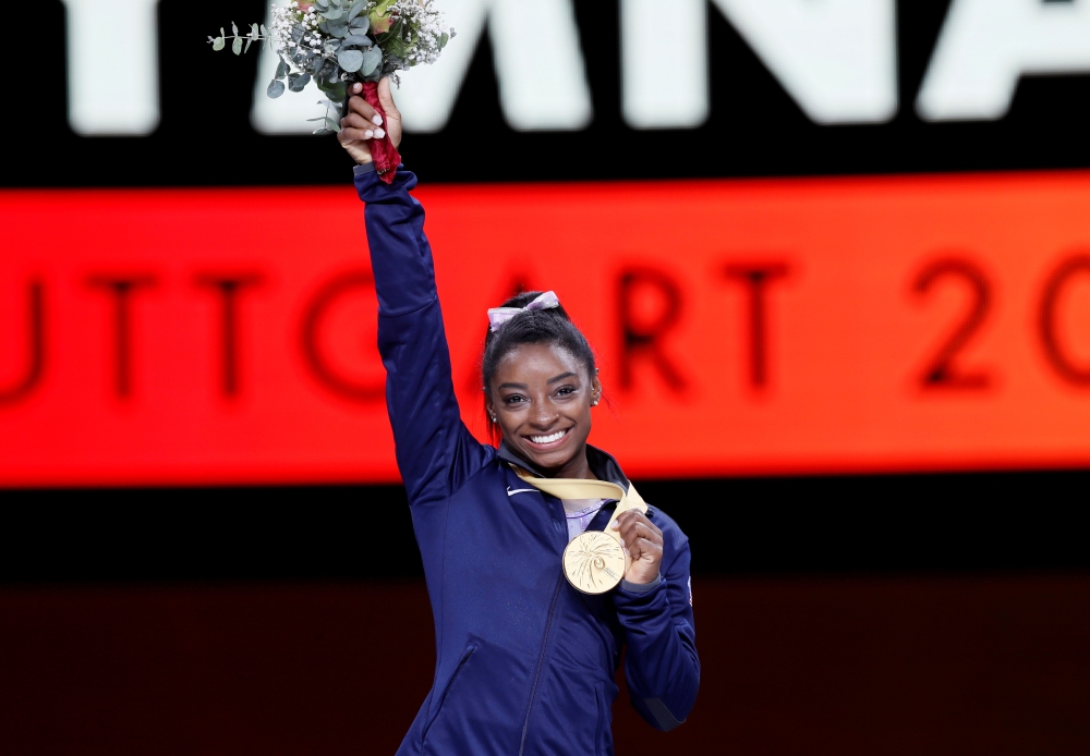 October 13, 2019 Gold medalist Simone Biles of the U.S. celebrates on the podium with her medal and flowers REUTERS/Wolfgang Rattay/File Photo