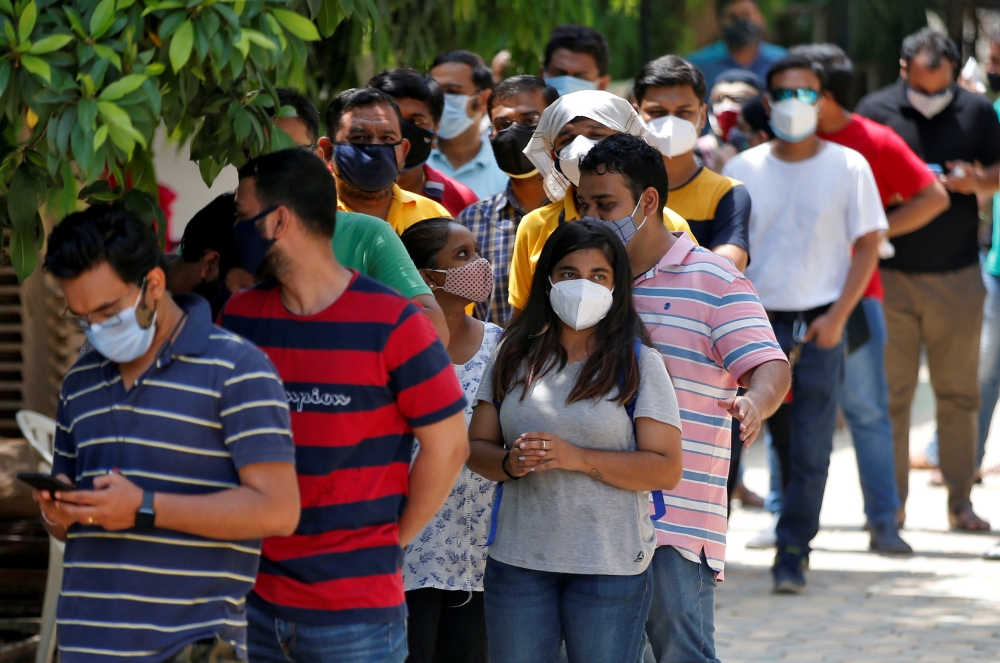FILE PHOTO: People wearing protective face masks wait to receive a dose of COVISHIELD, a coronavirus disease (COVID-19) vaccine manufactured by Serum Institute of India, outside a vaccination centre in Ahmedabad, India, May 1, 2021. REUTERS/Amit Dave/File
