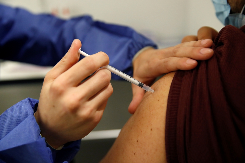 A medical worker administers a dose of the 