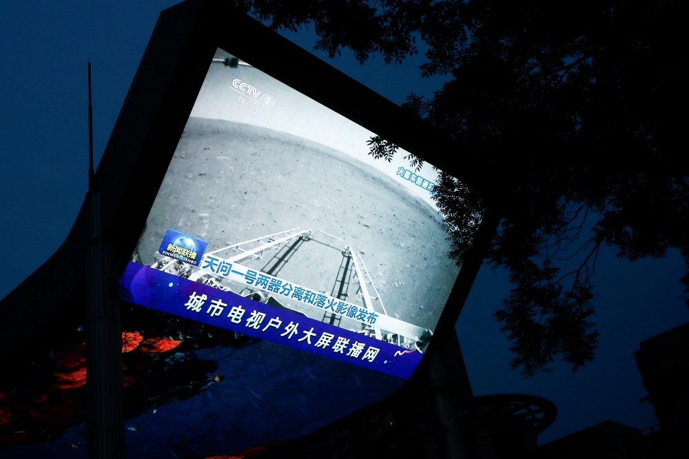 A screen broadcasts a CCTV state media news bulletin, showing an image of Mars taken by Chinese Mars rover Zhurong as part of the Tianwen-1 mission, in Beijing, China, May 19, 2021. Reuters/Thomas Peter 