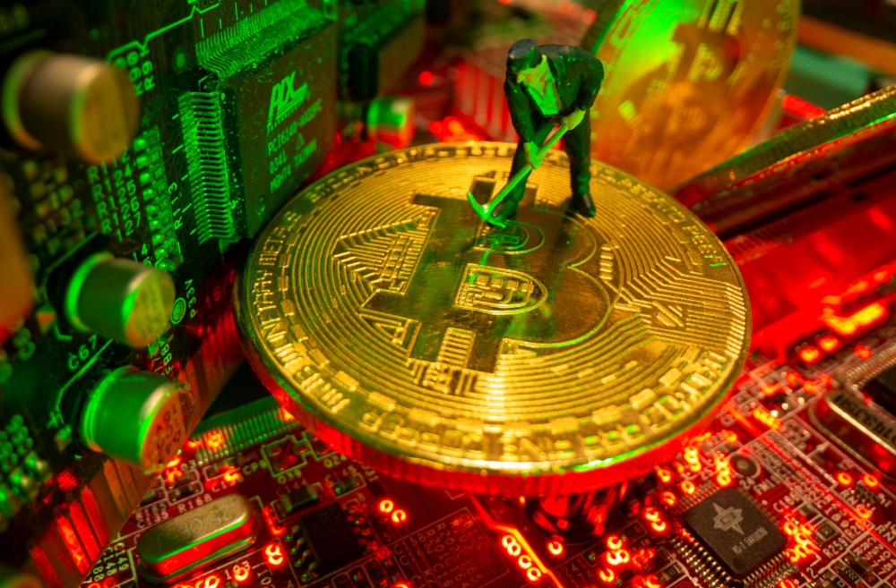 A small toy figure and representations of the virtual currency Bitcoin stand on a motherboard in this picture illustration taken May 20, 2021. REUTERS/Dado Ruvic/Illustration