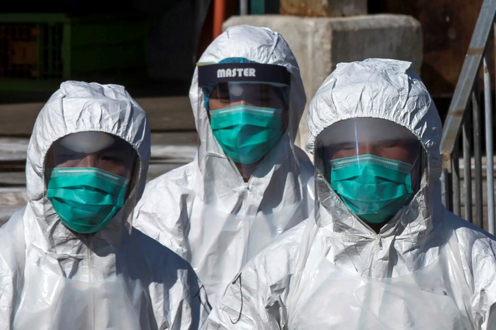 Health officers in full protective gear walk to a wholesale poultry market in Hong Kong December 31, 2014. REUTERS/Tyrone Siu/File Photo