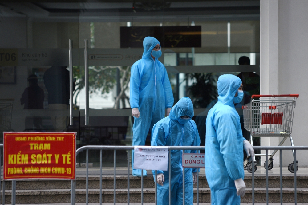 Medical workers in protective suits stand outside a quarantined building amid the coronavirus disease (COVID-19) outbreak in Hanoi, Vietnam, January 29, 2021. REUTERS/Thanh Hue/File Photo