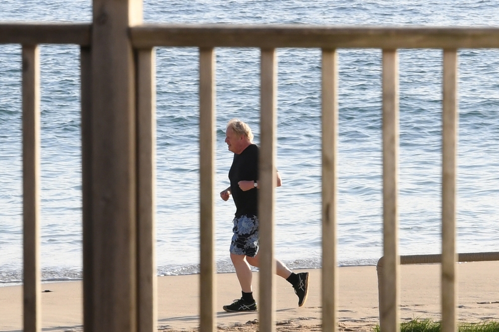 Britain's Prime Minister Johnson runs along the beach in Carbis Bay, during the G7 summit in Cornwall, Britain June 12, 2021. Stefan Rousseau/PA Wire/Pool via REUTERS